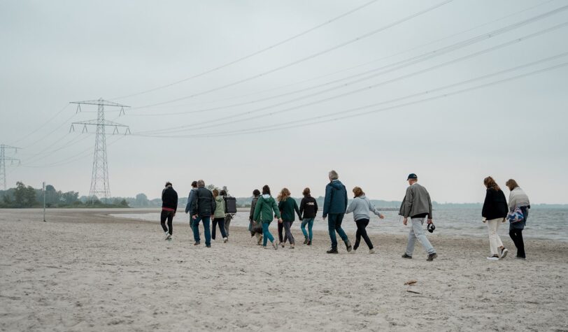 Groep mensen lopen over het Almeerderstrand langs het water tijdens de WaterWalks langs het IJmeer - Foto: Lidewij Meijer