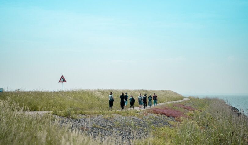 Groep mensen loopt over het fietspad langs de dijk tijdens de WaterWalks - Foto: Lidewij Meijer